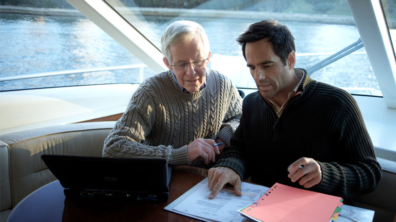 Two men sitting on a boat discussing finances