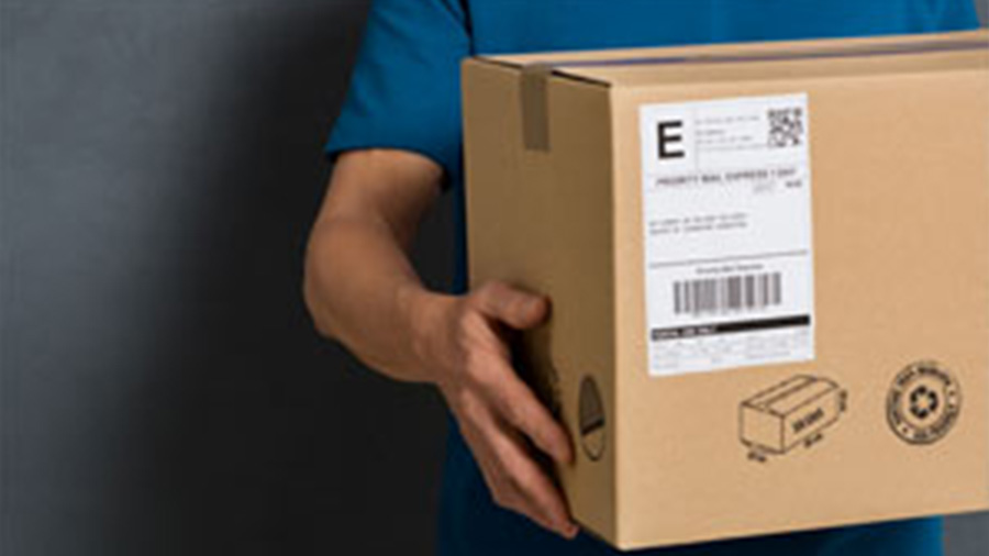 Ein Bild, das seit Corona wieder häufiger zu sehen ist: Ein Postbote liefert ein Paket nach Hause und verdeutlicht E-Commerce als Investment-Thema